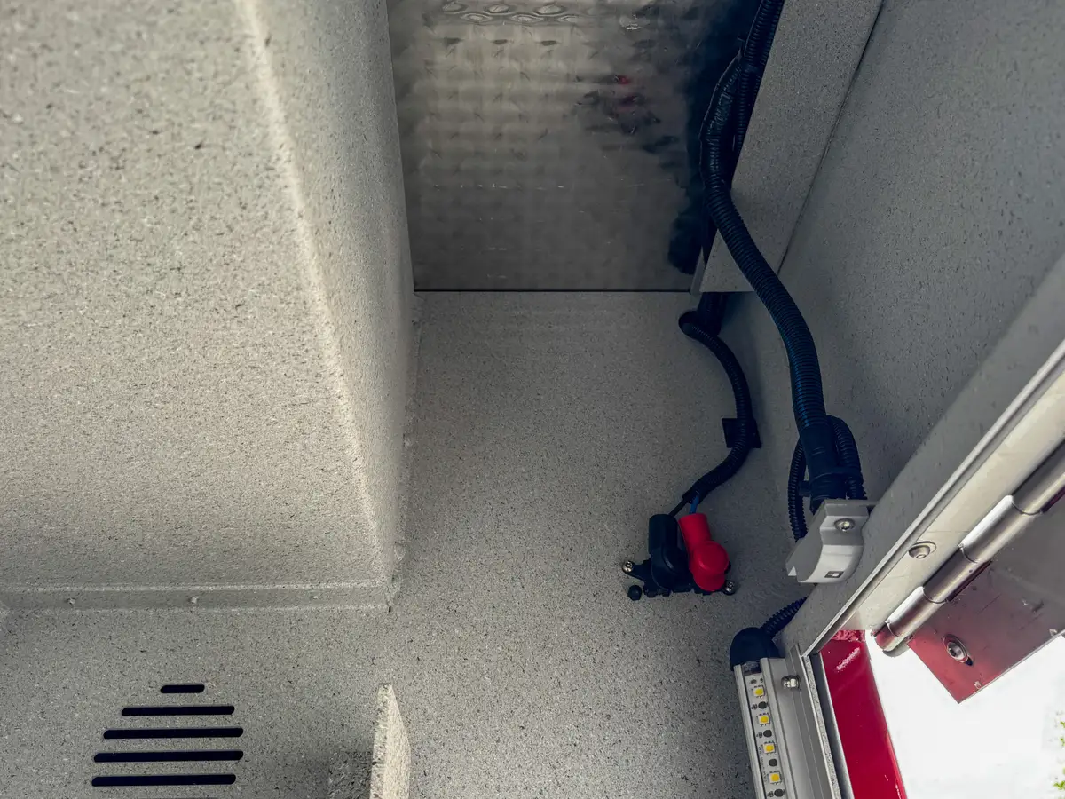 Compartment interior side view with shelf support bracket and wall panel.